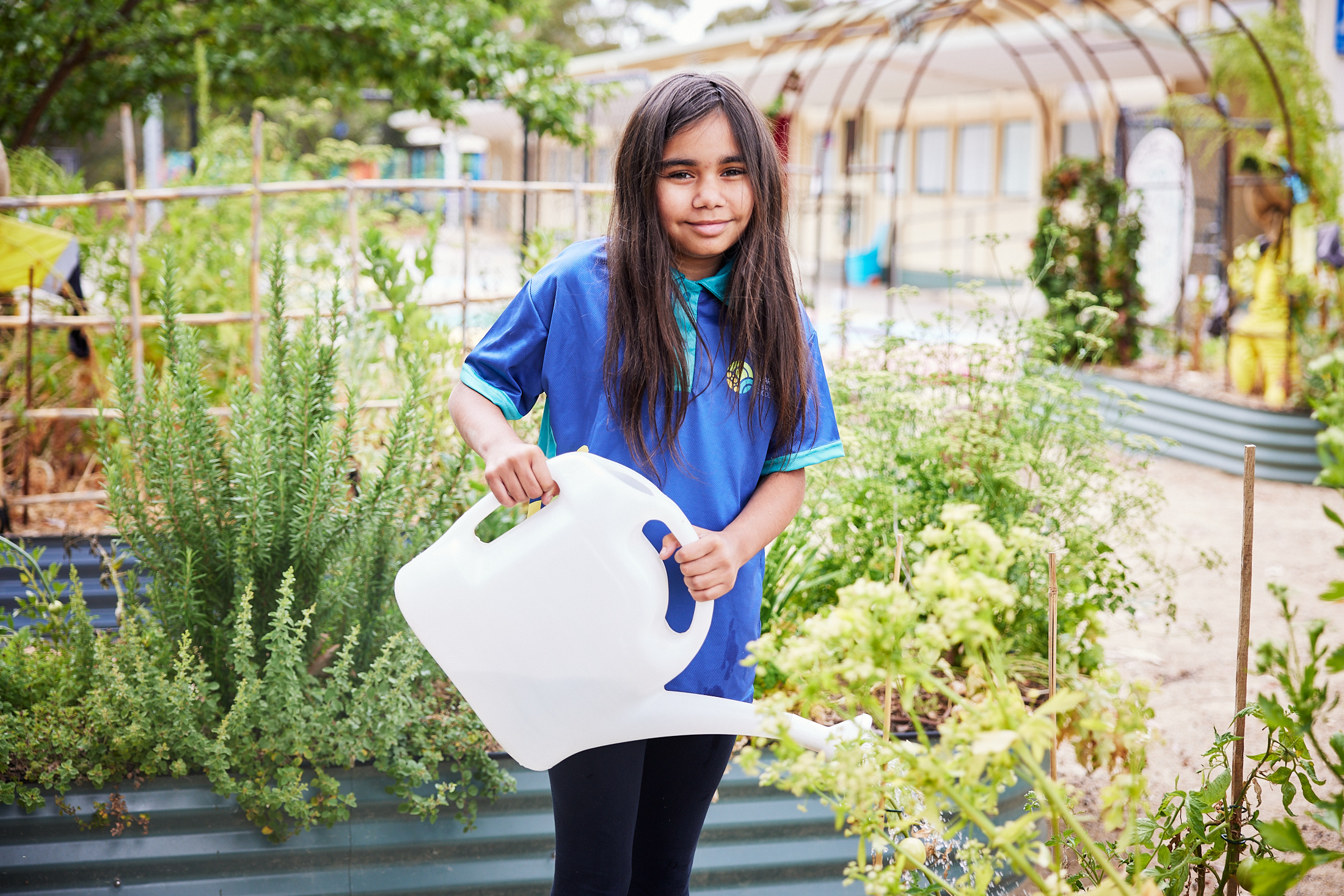 Girl with watering can in school garden