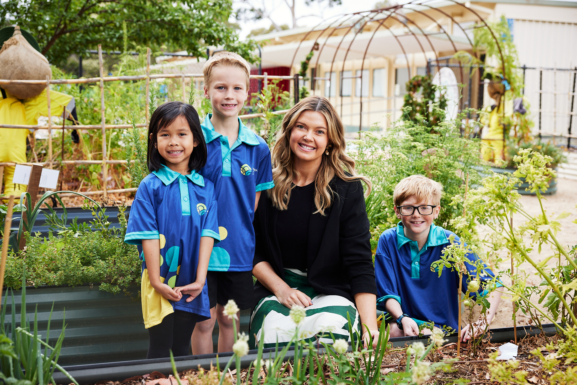 principal caitlin manser with three students in school garden